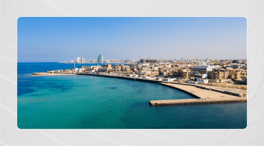 Photo of coastal shore in Benghazi, Libya featuring clear blue water and a surrounding city.